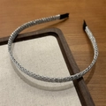 Detalle de una diadema fina plateada con textura tejida y puntas negras protectoras - Plateado