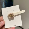 Detail of an ivory acetate hair clip with champagne gold rectangular crystal on card - Cream