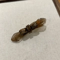 Detail of tortoiseshell acetate bow hair clip with textured wings on linen tray - Amber