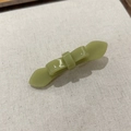 Detalle de una pinza para el pelo con lazo de acetato verde matcha sobre fondo de lino - Verde Frijol