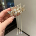 Detail van gouden vlinder haarklem met strassteen en lange bungelende kwastjesketting - Gouden Strass Vlinder