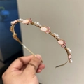 Dettaglio di elegante cerchietto dorato con cristalli a tulipano rosa e perle finte - rosa acceso