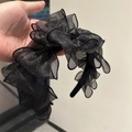 Detailansicht eines schwarzen Stirnbands aus Mesh-Gewebe mit feinem Glitzereffekt - Große Schleife Haarband