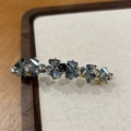 Dettaglio di un fermaglio dorato con cristalli blu e pietra preziosa nera centrale - Cristallo Blu