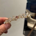 Dettaglio di un fermaglio dorato con cristalli trasparenti e una pietra centrale rosa - Rosa Chiaro