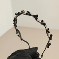 Serre-tête baroque perlé noir avec cristaux tenu par une main gantée - Noir