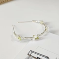 Detalle de diadema plateada con flores blancas, perlas y hojas verdes sobre fondo blanco - Estilo Perla