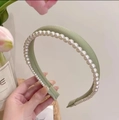 Detailed view of the light green satin headband featuring elegant white hand-set pearls - Green
