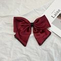 Gros plan sur un nœud de cheveux géant en satin bordeaux avec détails en perles noires - Nœud rouge vin