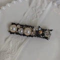 Detailaufnahme der Tweed-Haarspange mit weißen Perlen und schwarzer Kamelie auf Spitze - Schwarz