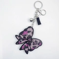 Vue détaillée du porte-clés nœud en cristal étincelant avec pompon en cuir et clochette - Léopard Rose
