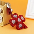 Red clover keychain with rhinestones and leather tassel on a decorative warm background - Red