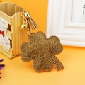 Detail of four-leaf clover keychain with rhinestones, golden bell, and brown leather tassel - Khaki