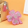 Detailed view of pink rhinestone clover keychain with tassel and bell accessory - Pink