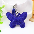 Velvet butterfly keychain with blue rhinestones and tassel hanging on a white table - Sapphire Blue