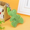 Detailed close-up of light green bear keychain with sparkling rhinestones and suede tassel - Green