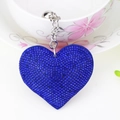 Macro shot of a blue heart-shaped rhinestone keychain with a small bell on a teacup - Silver And Royal Blue