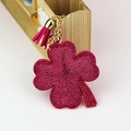 Close-up of sparkling magenta rhinestone clover keychain with golden chain and tassel - Rose Red