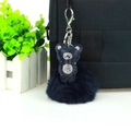 Detail of blue rhinestone bear keychain with matching fluffy fur pom pom on a black bag - Ink Blue