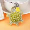 Detail eines gelben Schildkröten-Schlüsselanhängers mit Strass und Quasten am Tassenrand - Gelb