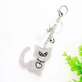 Dettaglio portachiavi a forma di gatto con strass, nappa bianca e campanello d'argento - Bianco
