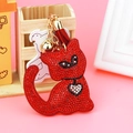 Dettaglio del portachiavi a gatto con strass rossi, campanello dorato e nappa in pelle - Rosso