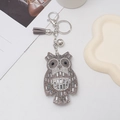 Detailed view of rhinestone owl keychain with grey suede tassel and silver metal hardware - Gray