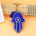 Detailed macro of Hamsa hand keychain with blue rhinestones and silk tassel - Blue