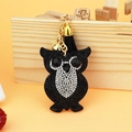 Detail of owl keychain with sparkling rhinestones, black tassel, and gold-tone bell accents - 60*50 / Black