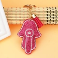 Detailed view of pink Hamsa hand charm with rhinestones, golden ring, and red tassel - Rose Red