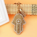 Detailed close-up of Hamsa Hand keychain with crystal rhinestones and leather tassel - Khaki