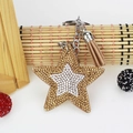 Detailed view of pentagram keychain with sparkling rhinestones and light brown suede tassel - Khaki
