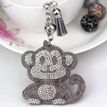 Close-up of cute monkey keychain with grey rhinestones, silver bell and suede tassel - Gray