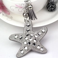 Starfish keychain with sparkling crystals and grey tassel on a white floral ceramic cup - Gray