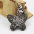 Détail du porte-clés papillon avec strass brillants et pompon à franges gris - Gris