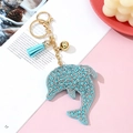 Sky blue crystal dolphin keychain with tassel and gold hardware on magazine backdrop - Lake Blue
