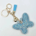 Sky blue butterfly keychain with rhinestones, golden bell, and tassel charm on white background - Lake Blue