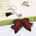 Primo piano di un portachiavi a fiocco con strass rossi brillanti e nappa nera - Rosso Nero Metallizzato