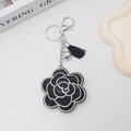 Dettaglio ravvicinato di un portachiavi a camelia nera con strass e nappe eleganti - Nero