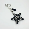 Detailed macro of leopard print star keychain with rhinestones, black tassel and silver clasp - Black