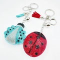 Détail de porte-clés coccinelle en strass rouges et bleus avec pompons et grelots - Couleur personnalisable