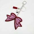 Dettaglio portachiavi a fiocco con strass rosa, nappa in pelle rossa e campanelli d'argento - Rosso Vino Con Riflessi Rosati