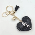 Close-up of black rhinestone heart keychain with lightning bolt and golden tassel detail - Black
