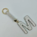 Golden keychain with letter M pendant fully encrusted with sparkling rhinestones - Style M