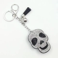 Detail view of rhinestone skull keychain with black leather tassel and silver metal hook - White