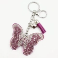 Détail d'un porte-clés papillon en strass violets avec pompon assorti et fermoir argent - Violet