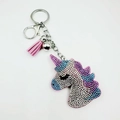 Macro detail of cartoon unicorn keychain with colorful rhinestones and pink leather tassel - Violet