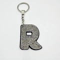 Detail of letter R keychain with colorful rhinestones on black velvet and silver ring - Letter R