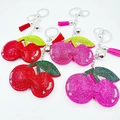 Détail de porte-clés cerise en cristal avec strass brillants et pompons soyeux - Couleur personnalisable