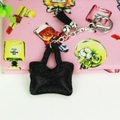 Vue détaillée d'un porte-clés mini sac noir avec chaîne argentée et pompon assorti - Noir